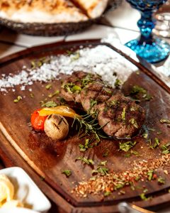 fried meat served with baked potato tomato rosemary leaf and slice of bell pepper